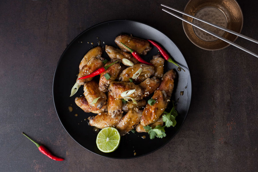 Alitas de pollo en un plato junto con palillos chinos para tomar