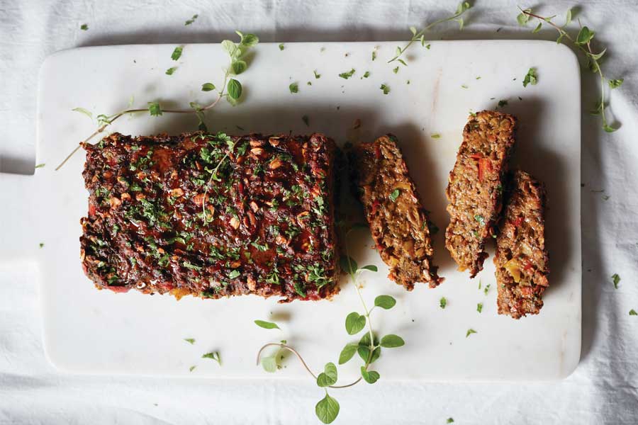 Pastel de verduras sobre una tabla blanca encima de un mantel blanco. 