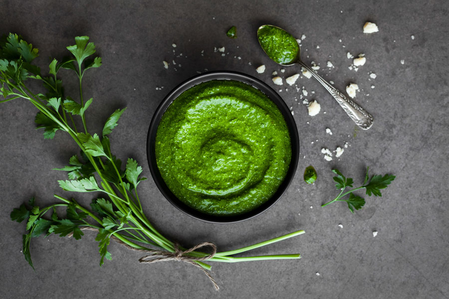 Pesto de espinacas y perejil en un cuenco con perejil fresco y una cuchara