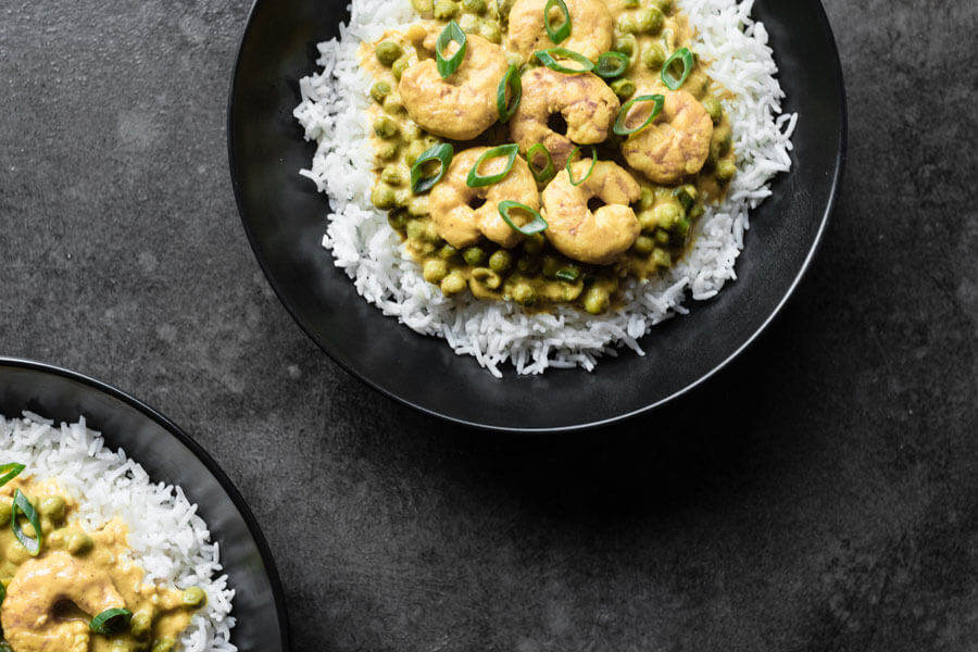 Curry de gambas con piña y guisantes sobre arroz en un plato