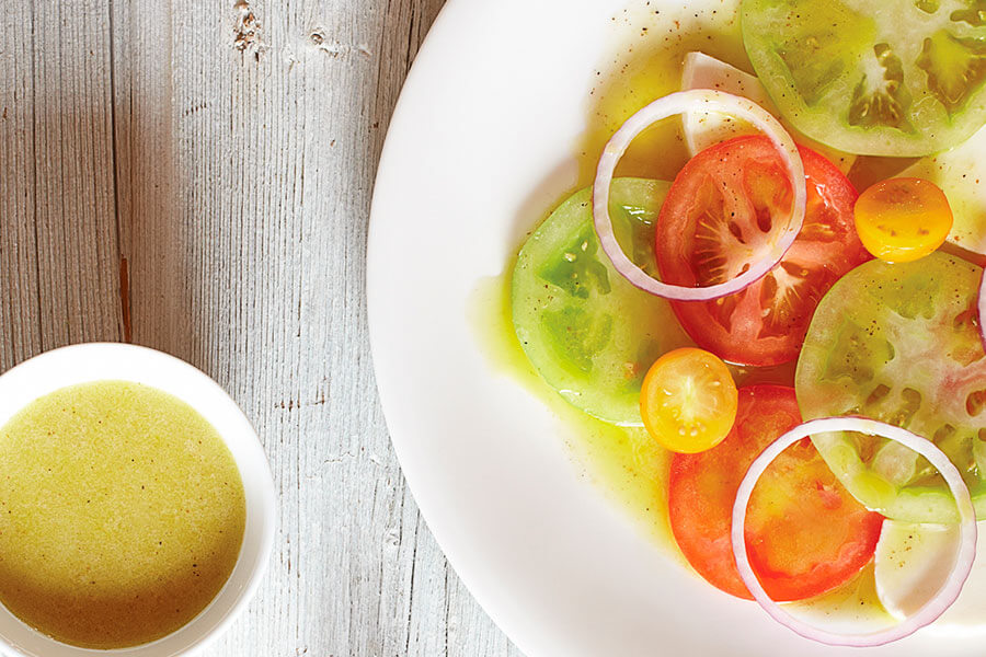 Vinagreta básica en un cuenco y aliñando una ensalada