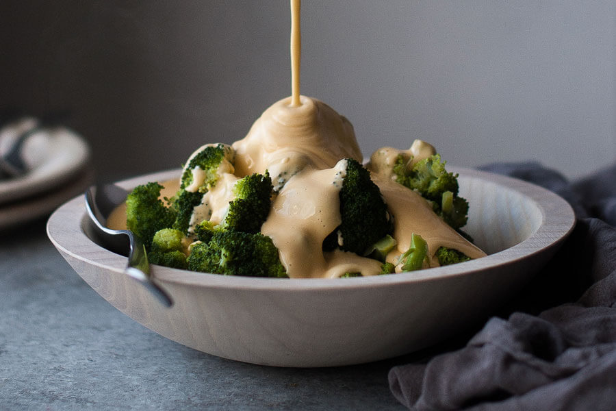 Brócoli cocido en un plato con salsa de queso Cheddar