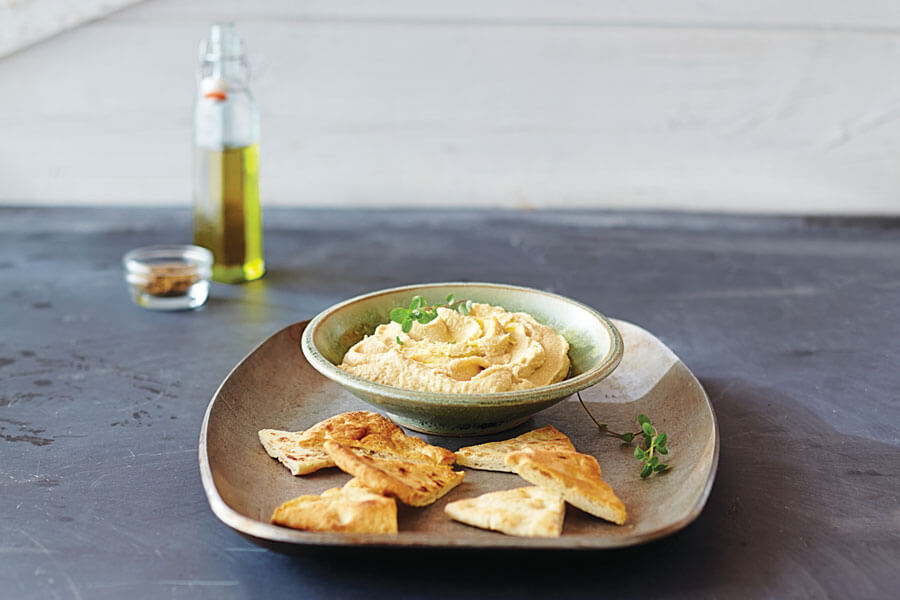 Hummus casero en un plato junto a trocitos de pan Hummus casero en un plato junto a trocitos de pan