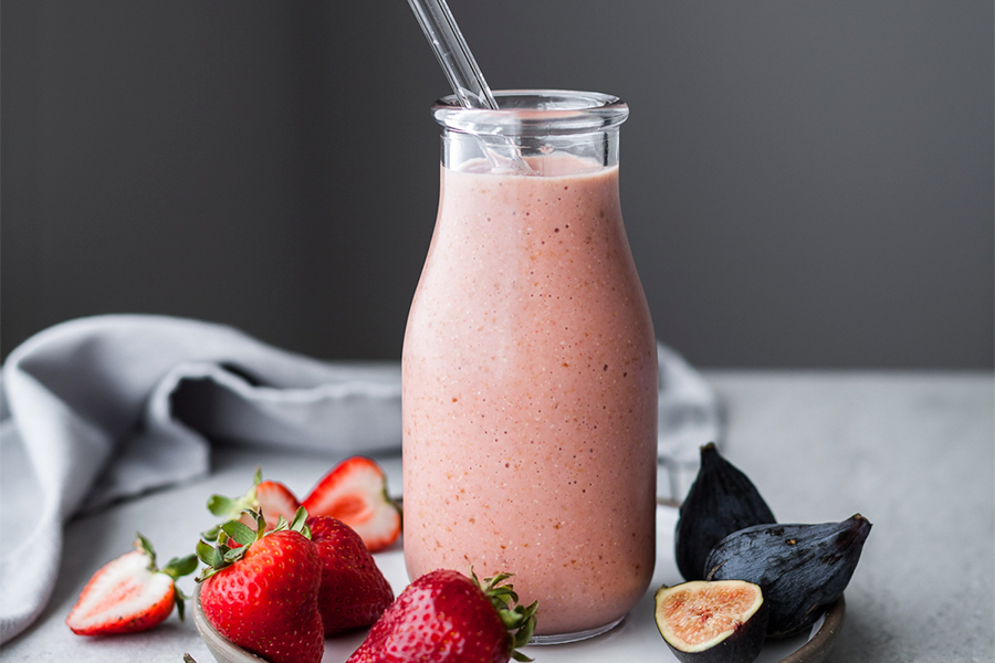 Batido antioxidante de fresa e higos en un vaso con una pajita